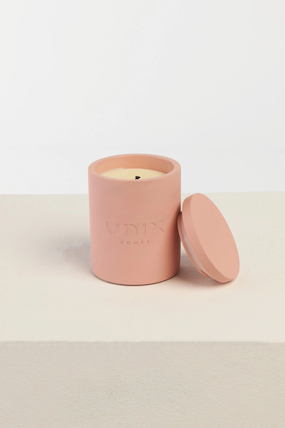 Pink scented candle close up UNIX logo embossed minimal - UNIX | شمعة معطرة بينك لقطة قريبة بلوجو UNIX بارز بتصميم بسيط - UNIX