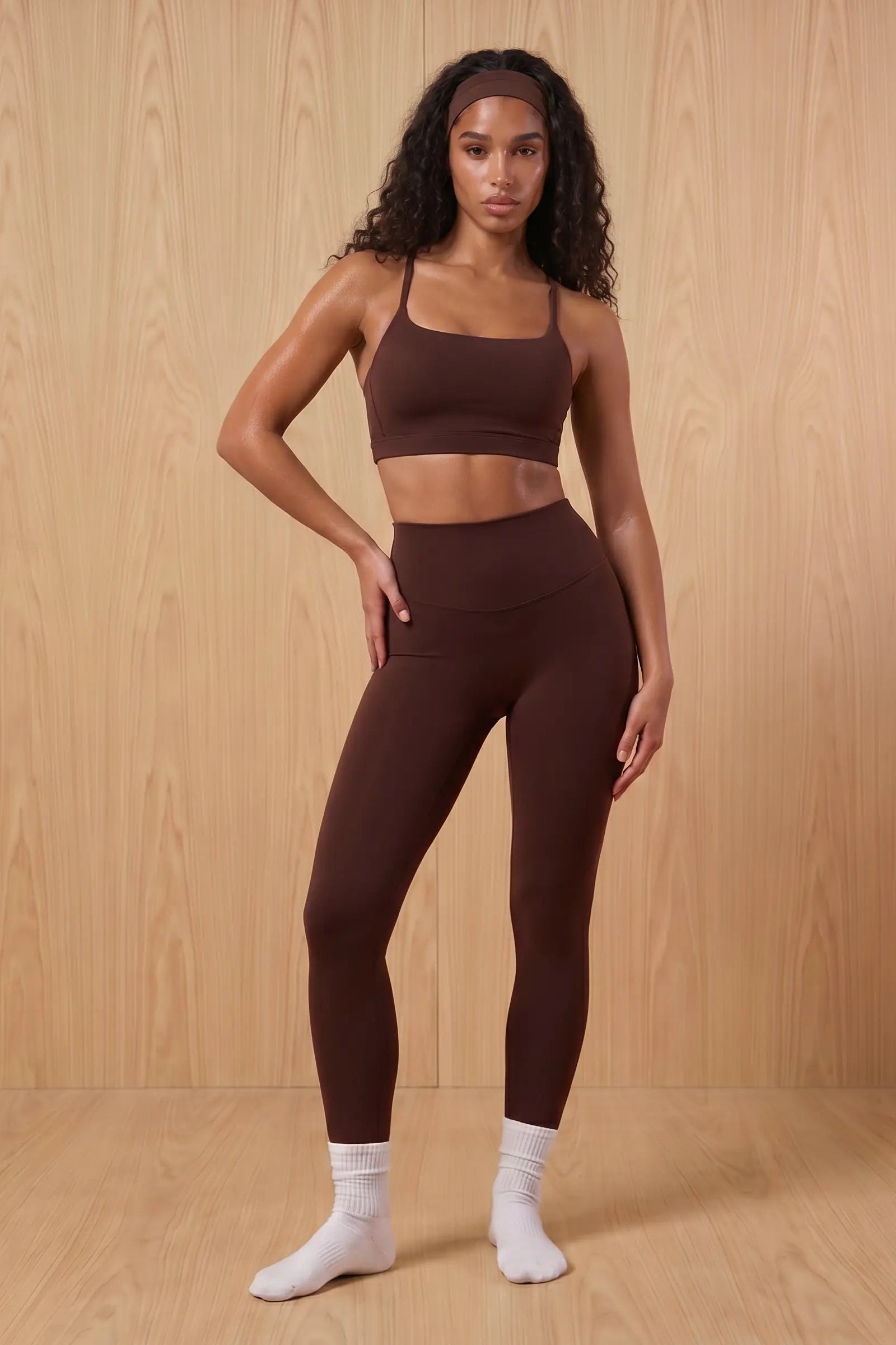 Woman wearing a brown sports bra and leggings set against a wooden background